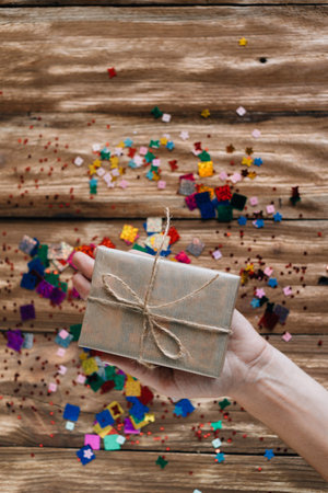 hand holds one box with a birthday present packed in craft paper