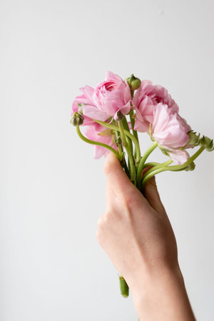 A bouquet of flowers in the hand of a girl on a white background.