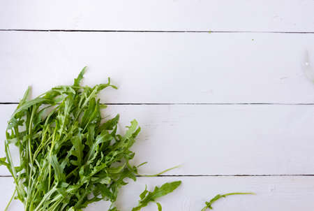 Fresh arugula salad leaves are lying on a wooden table. Place under the textの写真素材