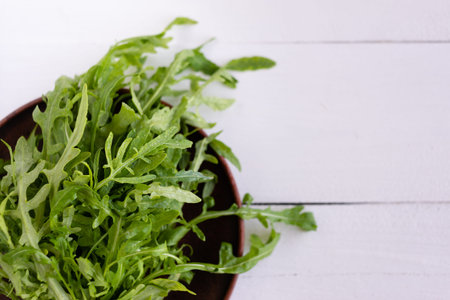 Arugula leaves are in a plate in the kitchen. Many vitamins and nutrients in them. Excellent syroeda...