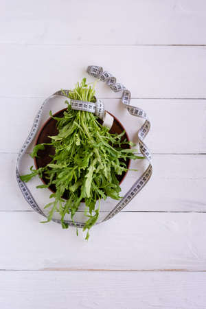 Arugula leaves are on the table, next to them is a flexible meter. Dietary food, a great way to get extra weightの写真素材