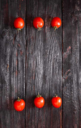 the rhythm of ripe and juicy cherry tomatoes, which lie in two rows on a table made of wood. Delicious and healthy food from natureの写真素材