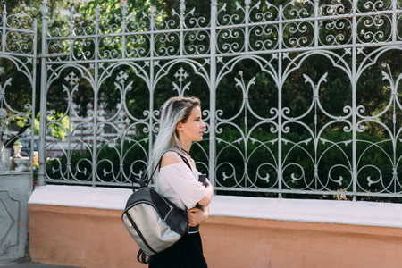 girl student on the background of a wrought fence goes to the university.