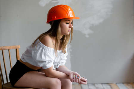 tired blonde girl repairman sitting resting on a chair. concept of cosmetic repairの写真素材