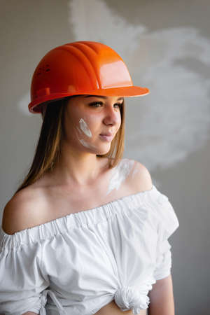 The girl makes repairs in the house. Wearing a white shirt and helmet on his headの写真素材