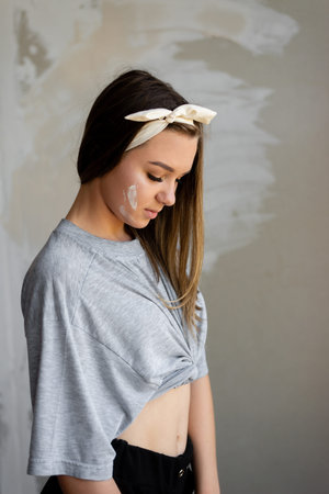 The girl is dressed in comfortable clothing that allows you to make repairs. T-shirt and shorts freely sit on it. Behind the wall, which the girl puttyの写真素材