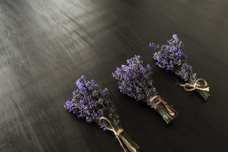 Three fragrant violet lavender bouquets on a dark background tied with decorative thread. Provencal...