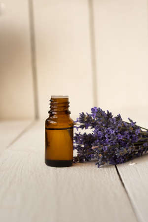 browbrown glass bottle with fragrant lavender oil and a bouquet of flowers. Aromatherapy for healthy sleep.n glass bottle with fragrant lavender oil and a bouquet of flowers.の写真素材