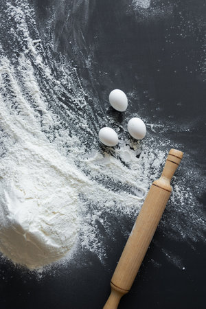 cooking cake, flour and eggs lie on a black background. Food production