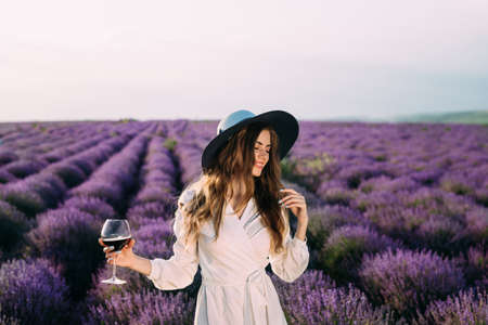 beautiful young girl holding a glass of red wine in a female hand. Holidays away from the city. Wine tasting in natureの写真素材