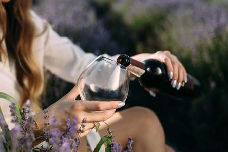 close up of female hands pouring red wine into a large glassの写真素材