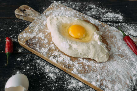 Homemade Ajarian Khachapuri with Sulguni Cheese Filled with a Raw Egg and Melted Butter Close Up. Fresh Hot Traditional Georgian Cheese-Filled Bread in the Form of a Boatの写真素材