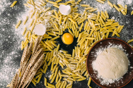 raw pasta on a dark background, fresh chicken egg, wheat flour and pastaの写真素材