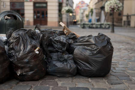 black garbage bags full lie on the streets of the city. Place for text.の写真素材