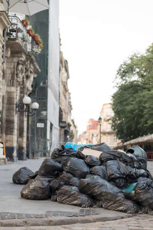 full garbage bags lie along the middle of the city street. Environmental pollutionの写真素材