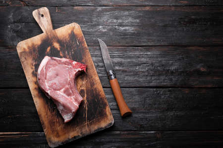 raw pork meat, a fresh piece lies on a cutting board, a kitchen table made of wood. Place for text.の写真素材