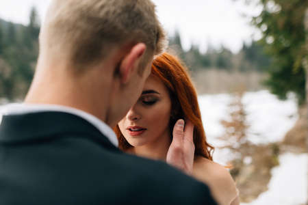 wedding in winter, beautiful young couple stand in the forest. Snow lies on the groundの写真素材