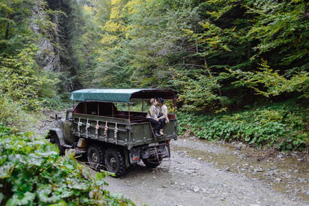 two young people kiss in a big car. People in camping clothes in the middle of the forest and mountains.の写真素材