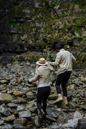 Friends go on a stony road. A woman and a man are walking in the park. A couple travels to beautiful places. Tourists go along the mountain road.の写真素材