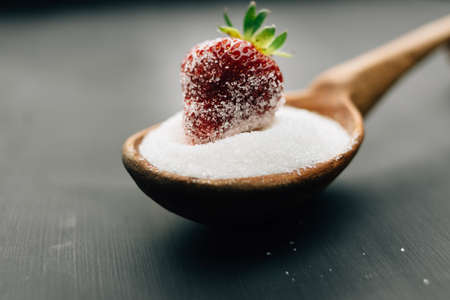 Full spoonful of sugar with strawberries on topの写真素材