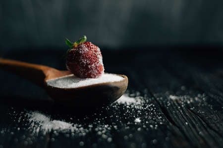 Spoon with sugar and strawberries on a dark backgroundの写真素材
