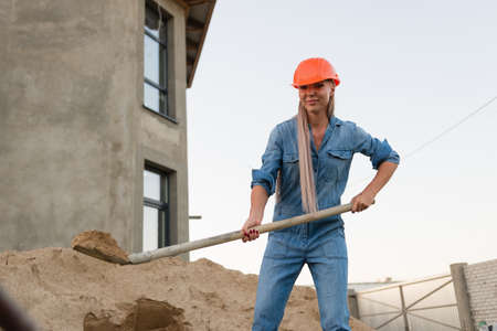 Woman working hard on construction site, holding shovelの写真素材