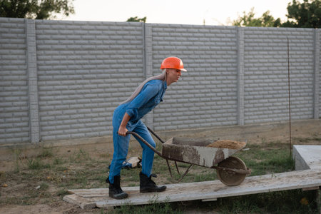 A woman works at a construction site, carries a sandcart