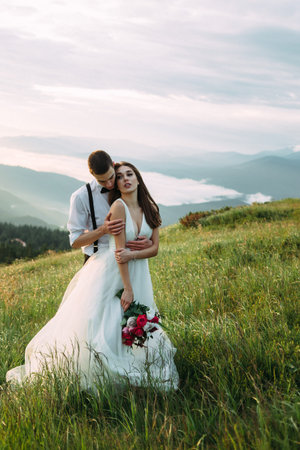 The bride and groom pose on the grass onの写真素材