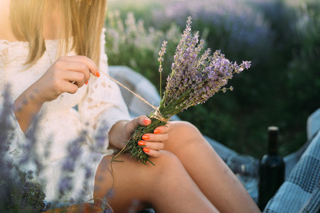 Unrecognizable woman on meadow holding lavender in her hands.
