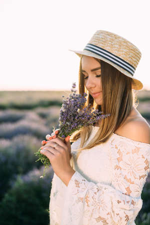 Girl in straw hat sniffs bouquet of lavender, close-upの写真素材