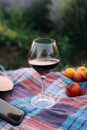 glass of wine on a bedspread, near fruit, a picnic in the middle of a lavender fieldの写真素材