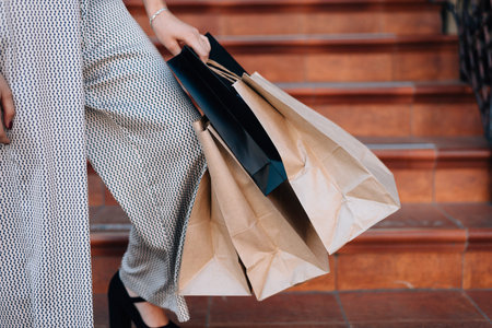 Bags with clothes in the hands of a girl, waist-high photo. A girl in a pantsuit poses after a...