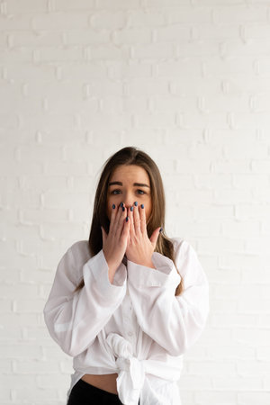 Young pretty woman wicovers mouth with shock, finds out awful bad news, being frightened by...