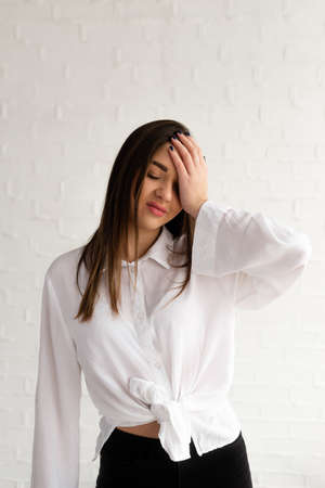 Portrait of young disappointed woman holding her head with hand. Isolated over white background. Emotion disappointedの写真素材