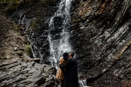 stylish young couple kisses near a waterfall, travel around the world, active lifestyle