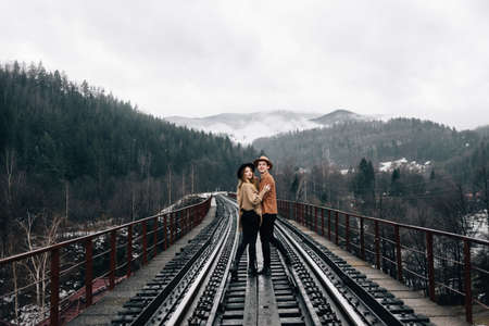 Two adventurers a guy and a girl walking on the railway. Men's brown hat and active lifestyle. Place for textの写真素材