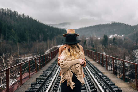 young stylish couple of hipsters are standing on the railway bridge. Young adventurers are wearing hats. Place for your text.の写真素材