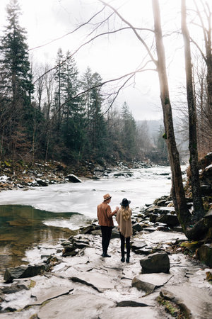 Young stylish couple, guys in love walk in the fresh air. Spring on the street. The river is...
