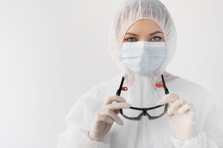 protection against coronavirus, close-up portrait of a woman dressed in a protective suit takes off...