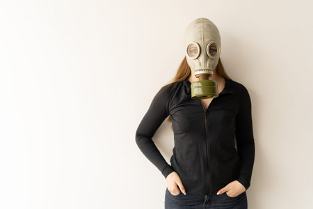 woman in gas mask dressed in a black sweater and jeans on a white background. Place for text