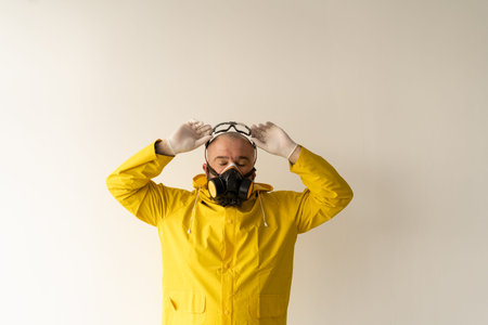 a man dressed in a yellow protective suit puts glasses on his face. Protection against viruses and...