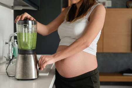 close-up hands of a pregnant woman, the process of making smoothies. Tasty and healthy food. Healthy eating while expecting a babyの写真素材