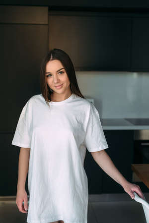 Sexy female body early in the morning in the kitchen in a white T-shirt without. place for textの写真素材