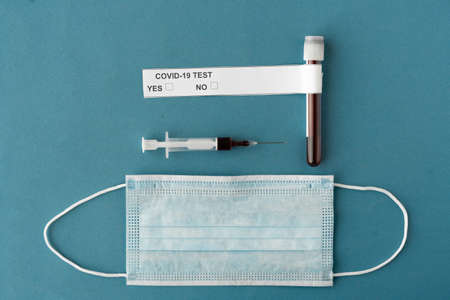 blood sample to test for coronavirus, test tube and syringe with blood on a blue background. Face mask. Place for textの写真素材