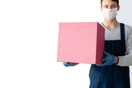 delivery of goods during quarantine. A man is wearing a protective mask and blue gloves holding a large box. Place for textの写真素材