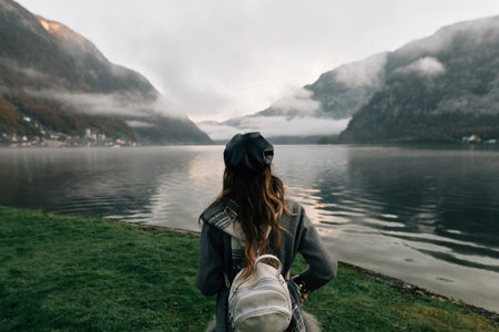 a young woman is standing by the lake. Early morning fog over the mountains. Holidays in the...