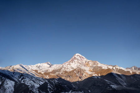 Mount Kazbek in the snow and the village of Stepantsminda in Georgia. Dawn in the mountains and the...