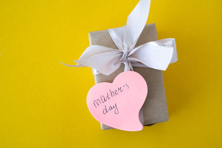 gift box with text mothers day bow on a yellow background. Gift for Valentine's Day, Mother's Day, Women's Day. A gift for people. place for text. banner. card.の写真素材