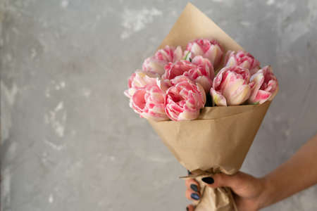 horizontal frame a large bouquet of tulips, a female hand holds flowers. A gift for mom on holiday. International Women's Day, Mother's Day. Place for textの写真素材