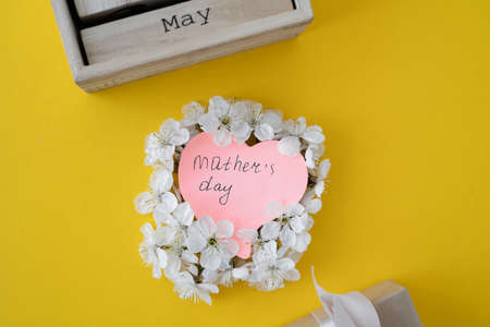 mother's day celebration concept. Wooden calendar month of May. Yellow background. Blooming cherry. Place for textの写真素材